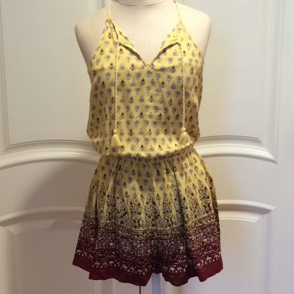 Yellow romper with white, black and maroon print.